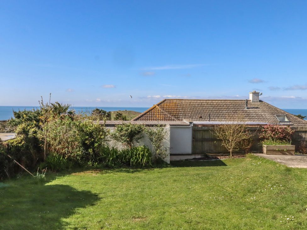 A garden with grass and a house in the background at Highdown Bigbury on Sea near Modbury