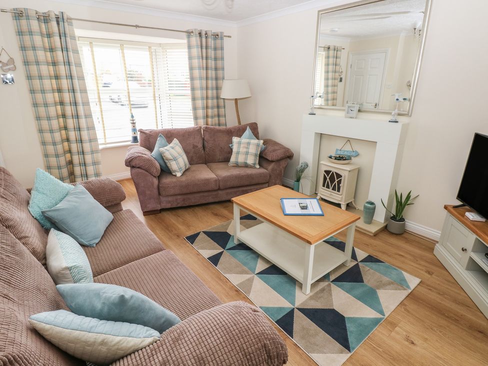 A living room with sofas, a table, and a television at Sandyhill House in Saundersfoot