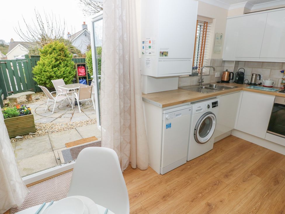 A kitchen with a washing machine and door opening to a garden at Sandyhill House in Saundersfoot