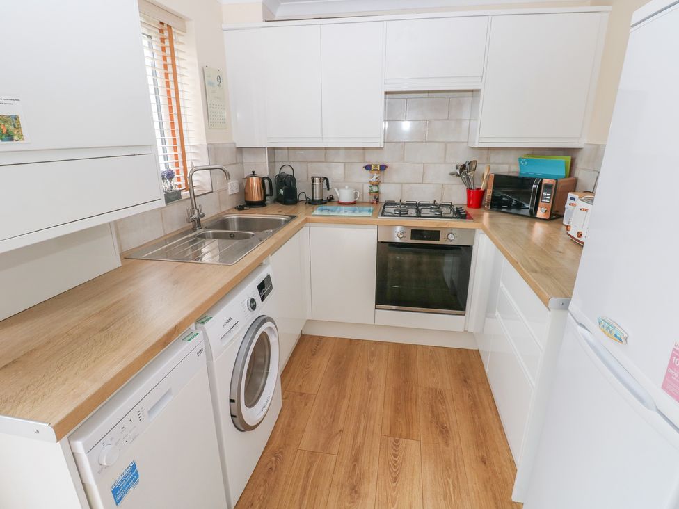 A kitchen with a washing machine and gas stove at Sandyhill House in Saundersfoot