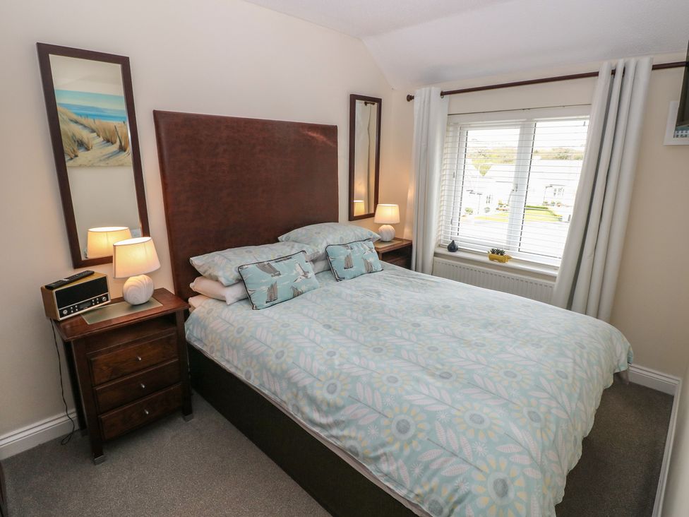 A bedroom with a double bed and window at Sandyhill House in Saundersfoot