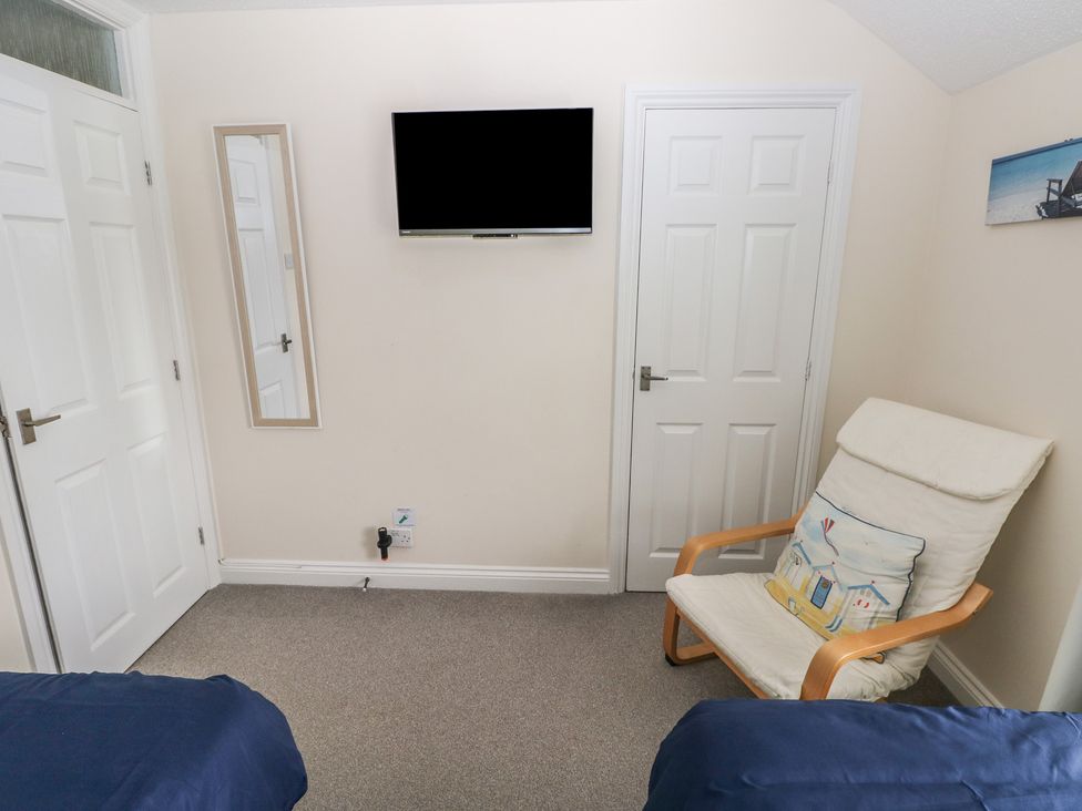 A bedroom with a TV and a chair at Sandyhill House in Saundersfoot