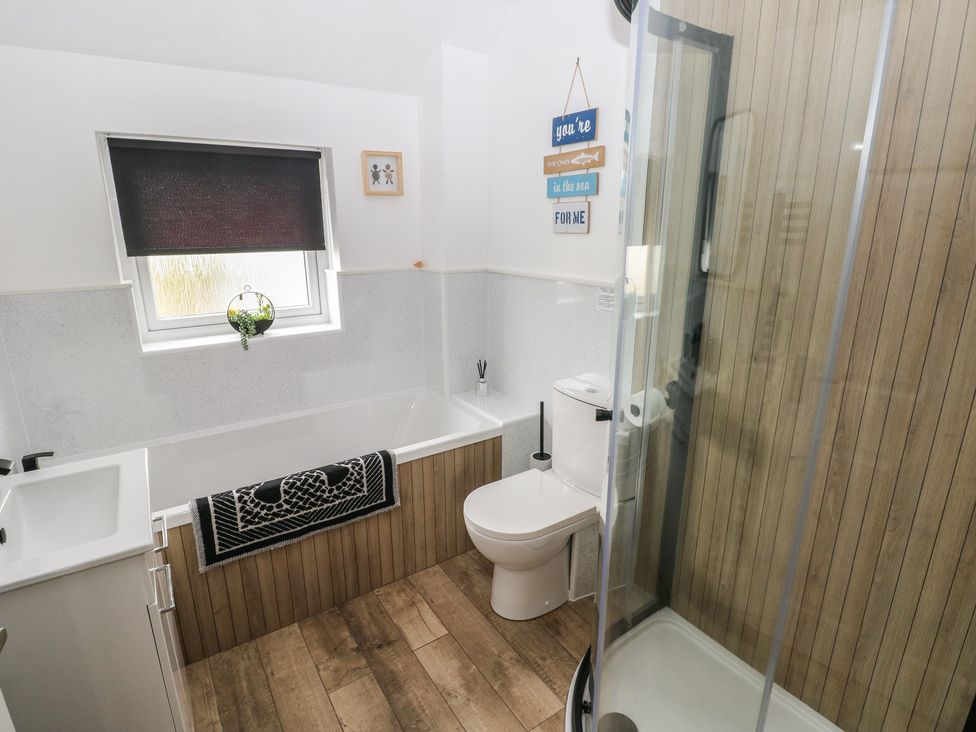 A bathroom with a bathtub, shower, sink, and toilet at Sandyhill House in Saundersfoot