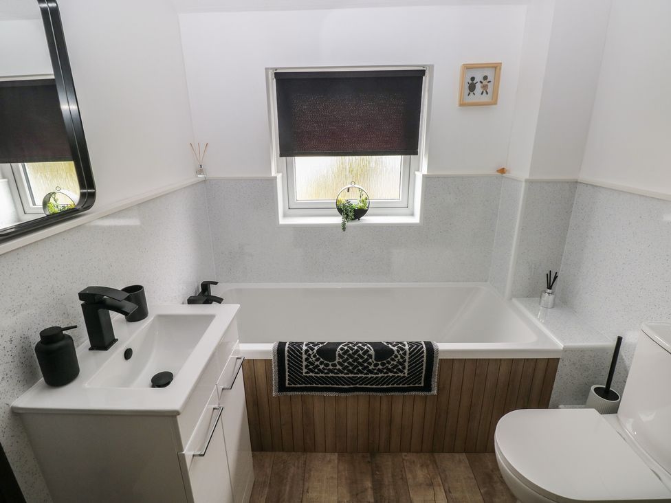 A bathroom with a bath tub, sink, and toilet at Sandyhill House in Saundersfoot