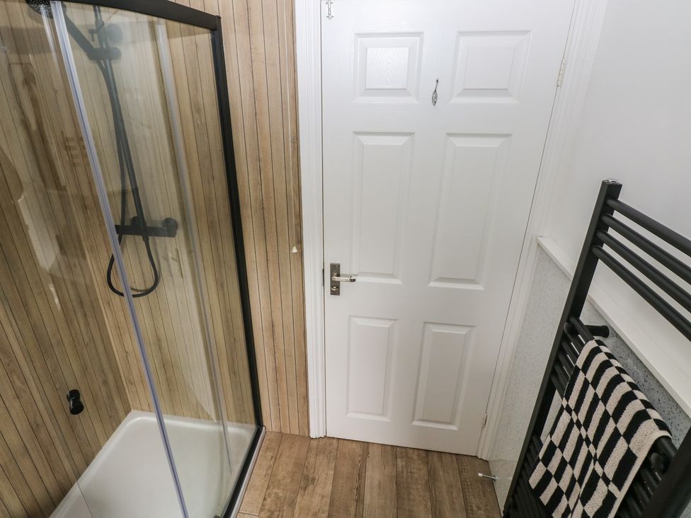 A bathroom with a shower and towel rail at Sandyhill House Saundersfoot