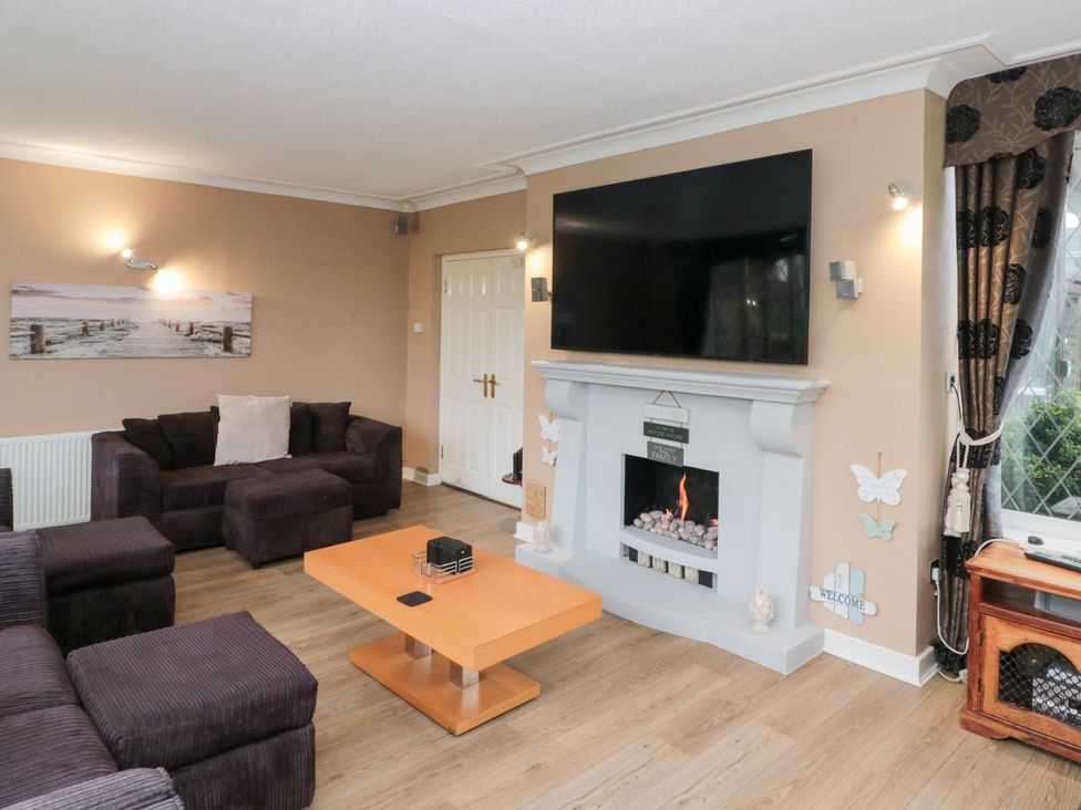 A living room with a sofa, coffee table, and television at Seacrest Lodge in Scarborough