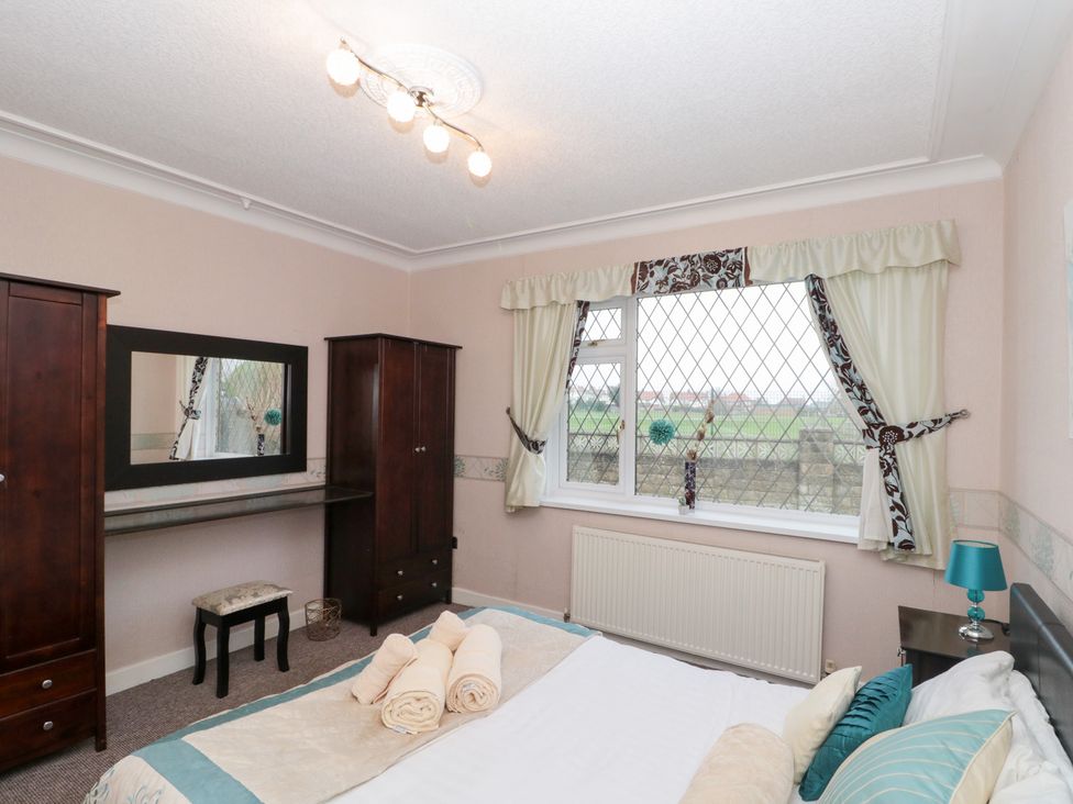 A bedroom with a bed, wardrobe, and window at Seacrest Lodge in Scarborough