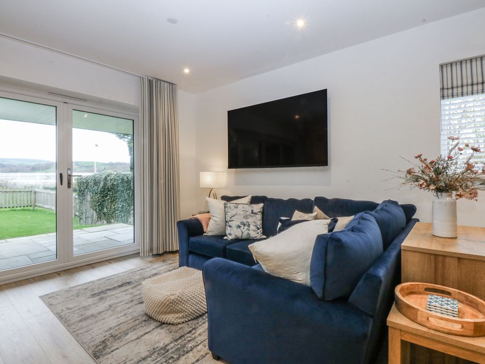 A living room with a blue sofa and television at Estuary View in Colwyn Bay