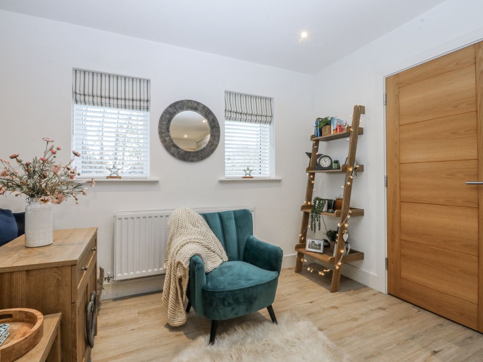 A snug with an armchair and shelving unit at Estuary View in Colwyn Bay