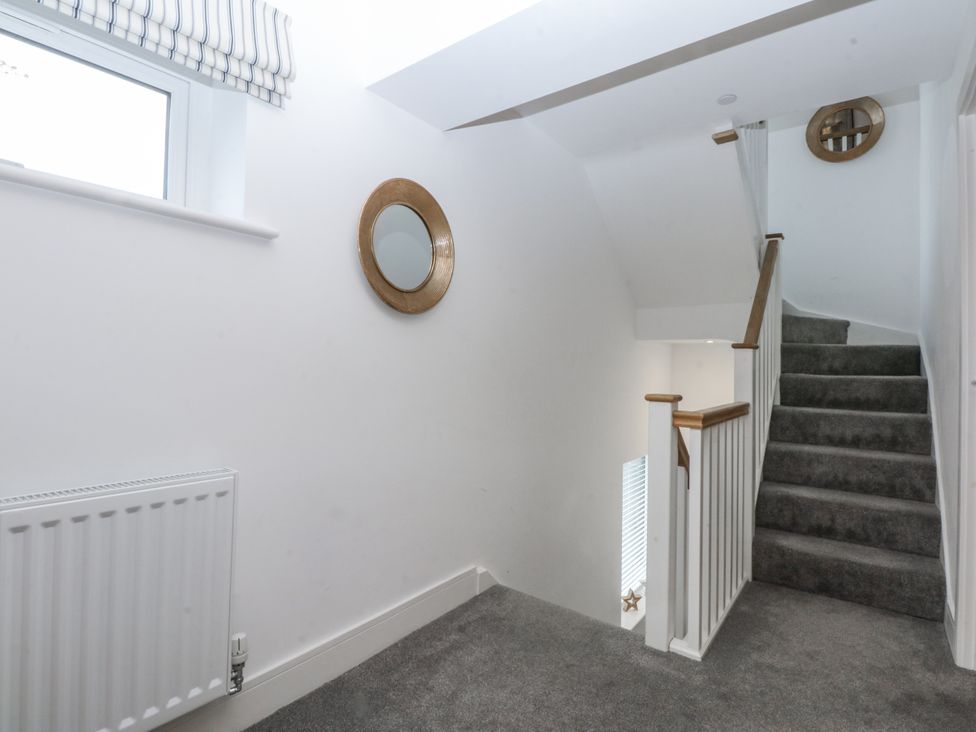 A hallway with a staircase and a mirror at Estuary View in Colwyn Bay