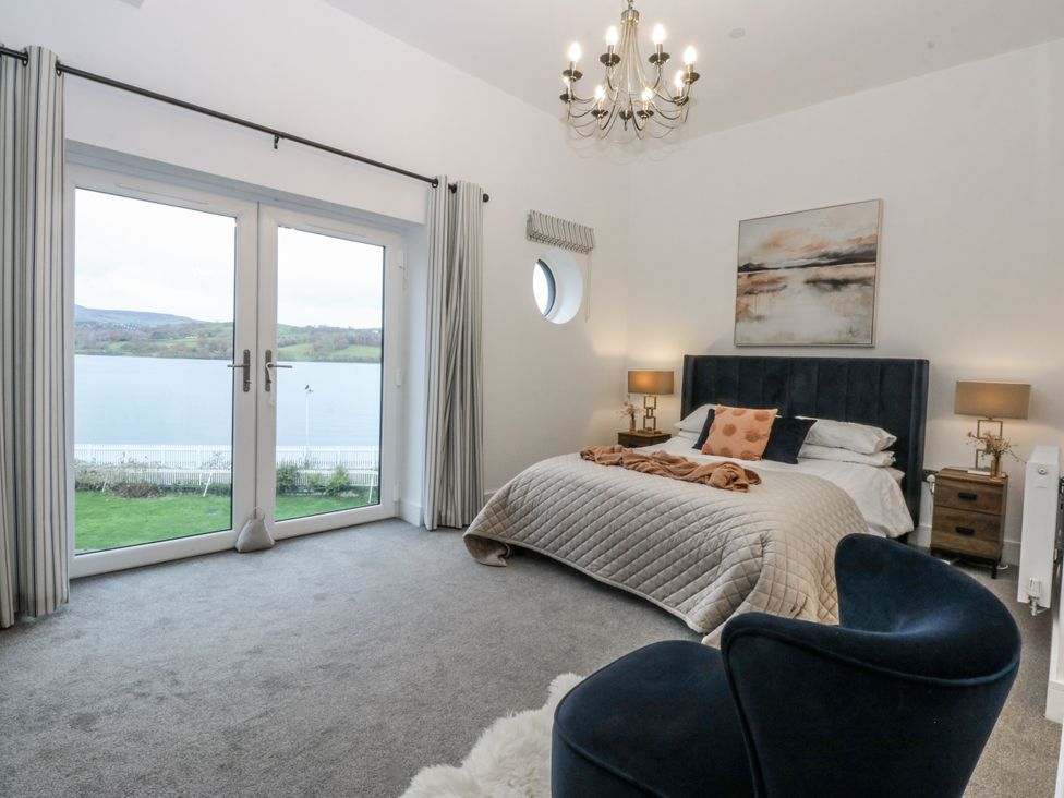 A bedroom with a bed and windows at Estuary View in Colwyn Bay