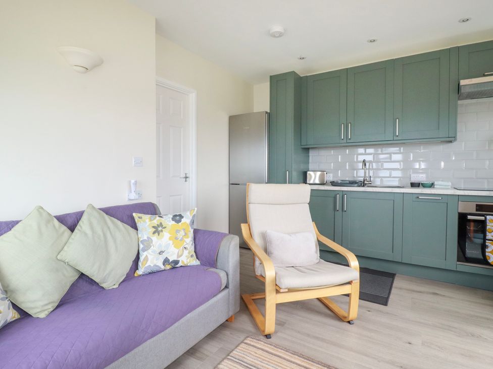 A living room with a sofa and kitchen area at Kitticarn Sennen Cove near St Just