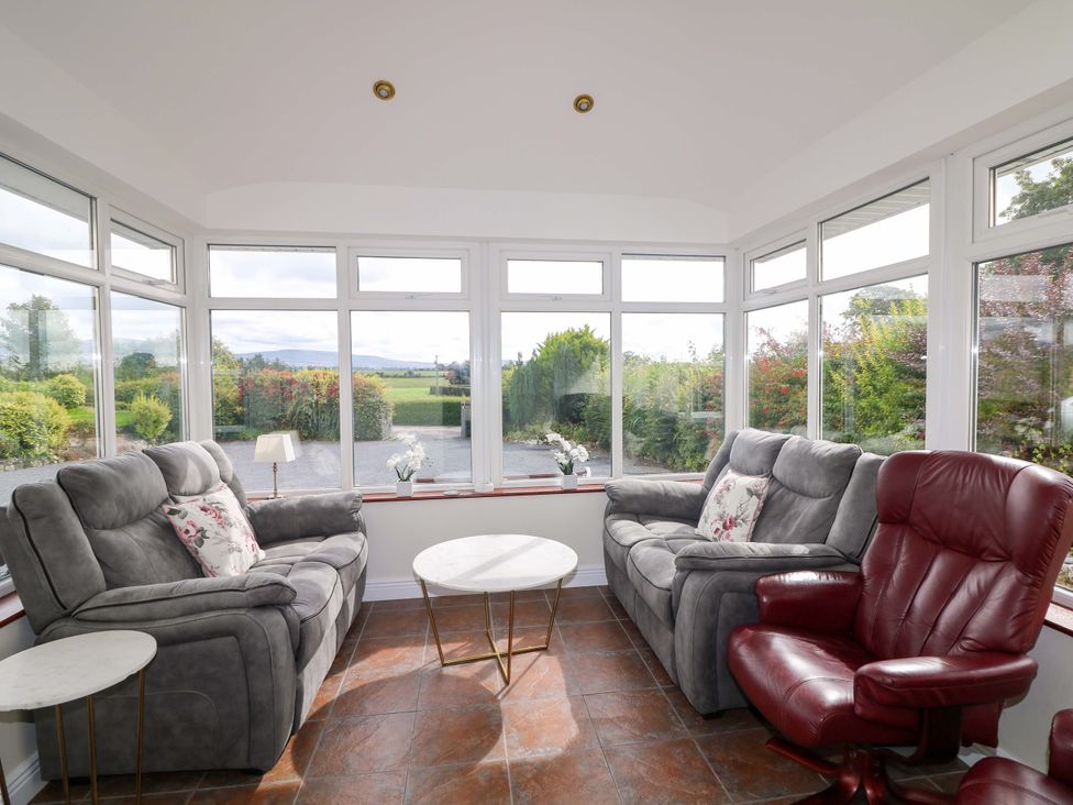 A conservatory with sofas and a coffee table at Curradoon House, Touraneena, County Waterford