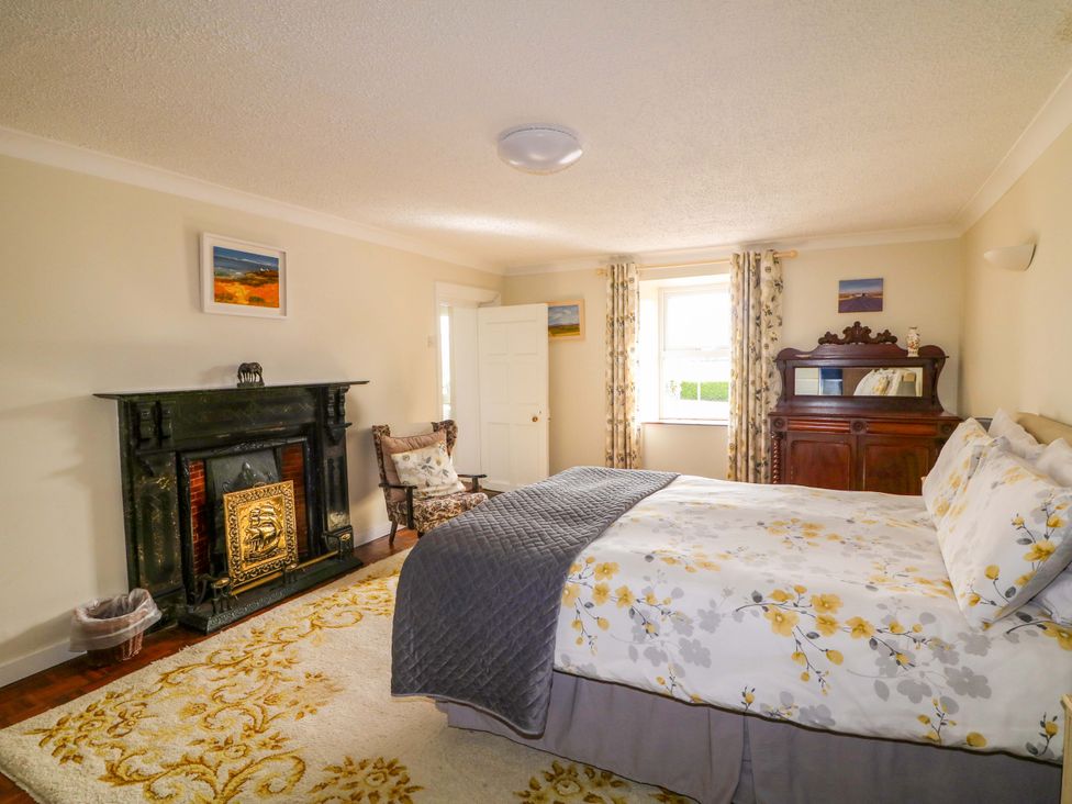 A bedroom with a bed and a fireplace at Curradoon House, Touraneena, County Waterford