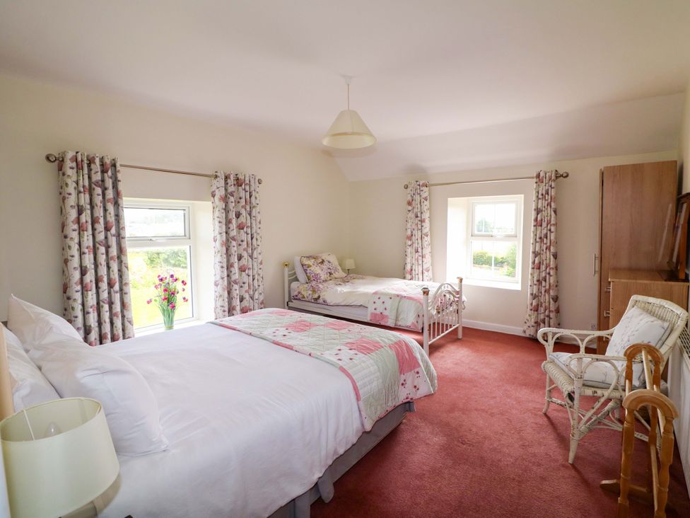 A bedroom with two beds and a window at Curradoon House in Touraneena, County Waterford