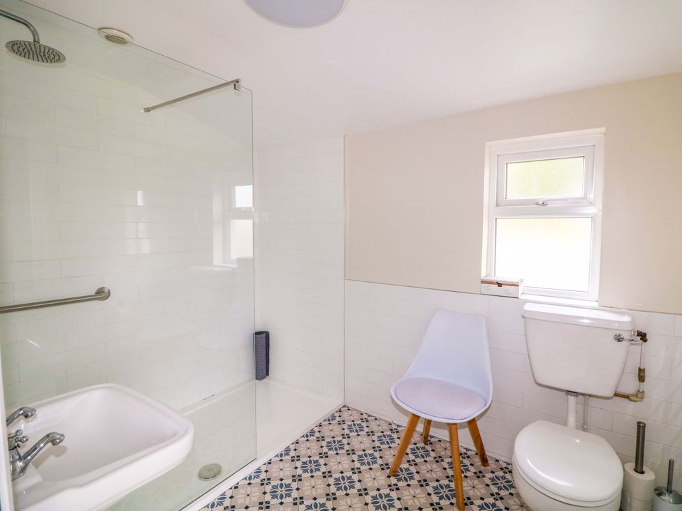 A bathroom with a shower, toilet, sink, and window at Curradoon House in Touraneena, County Waterford