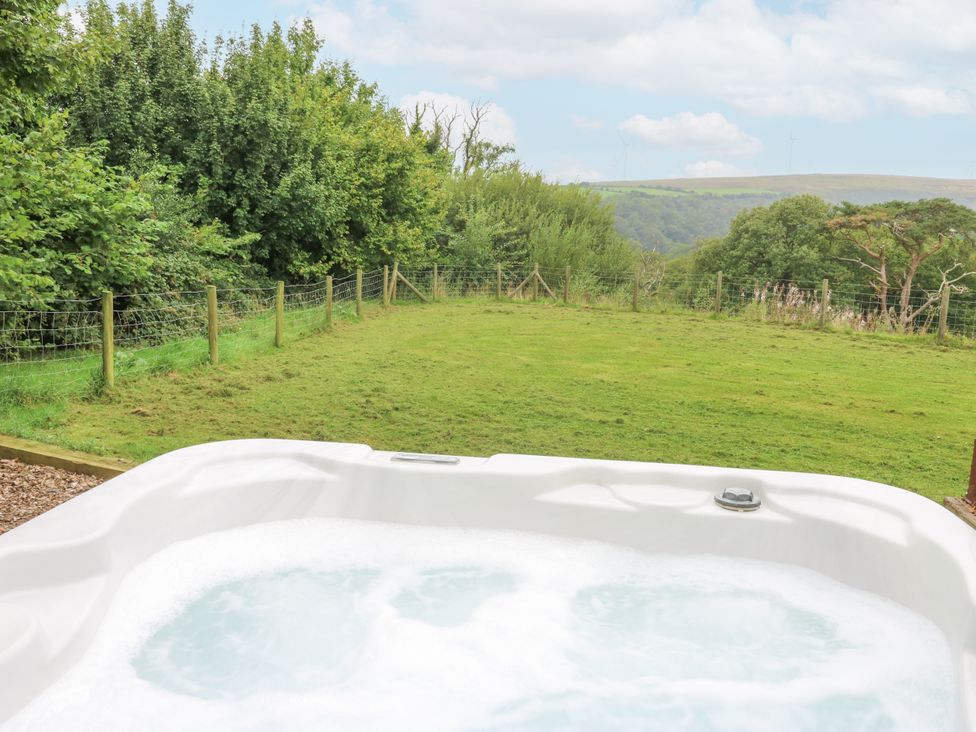 A garden with a hot tub and grass area at The Cabin in Pontardawe