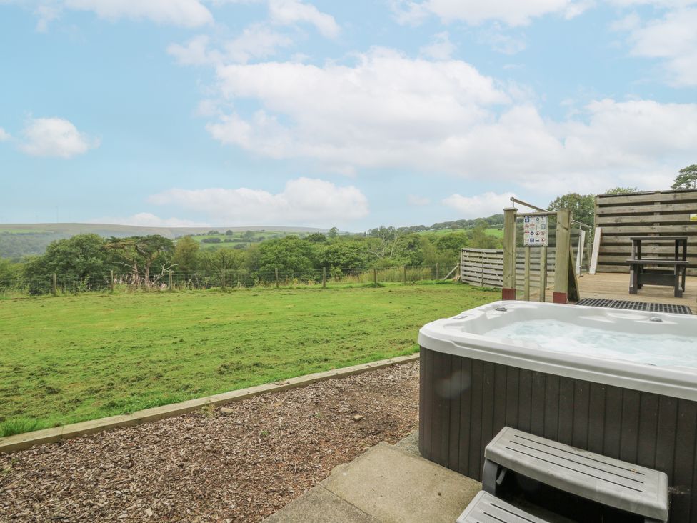 A hot tub with steps nearby and grassy area at The Cabin in Pontardawe