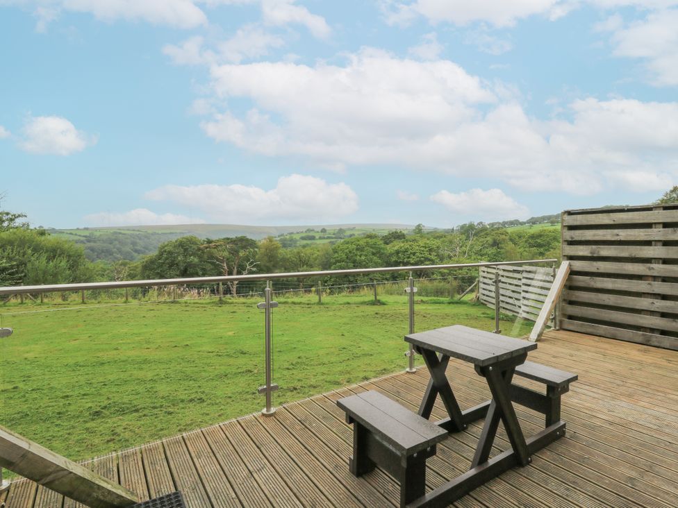 An outdoor space with a table and benches overlooking a landscape at The Cabin in Pontardawe