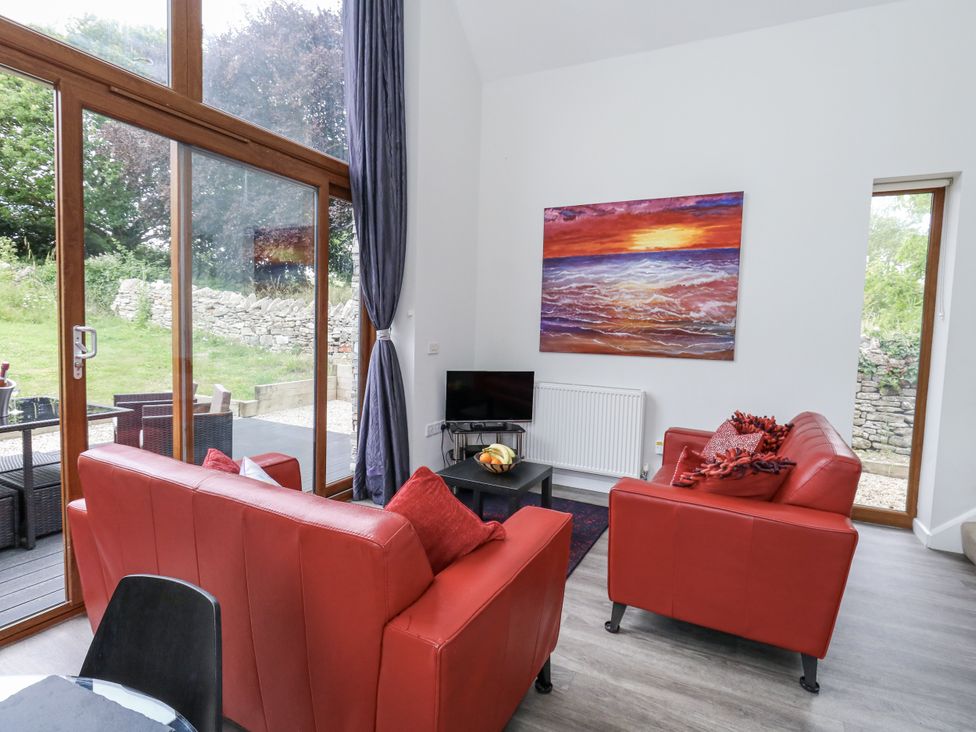 A living room with red sofas and a television at Budmouth in Upwey near Weymouth