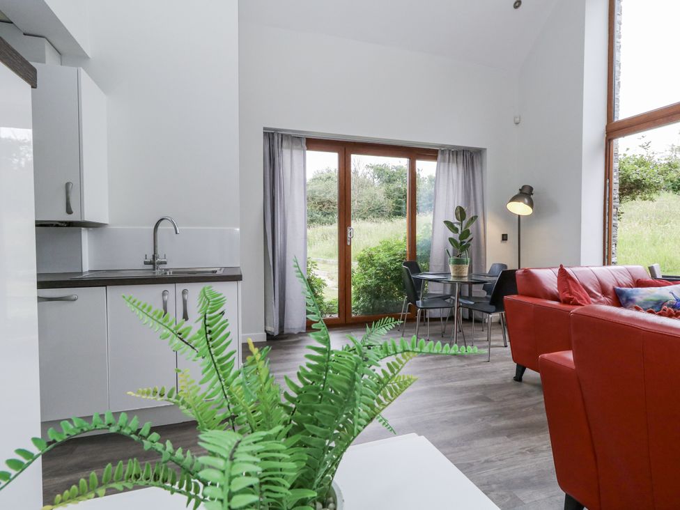 A living room with a kitchen sink, dining table and chairs at Budmouth Upwey near Weymouth