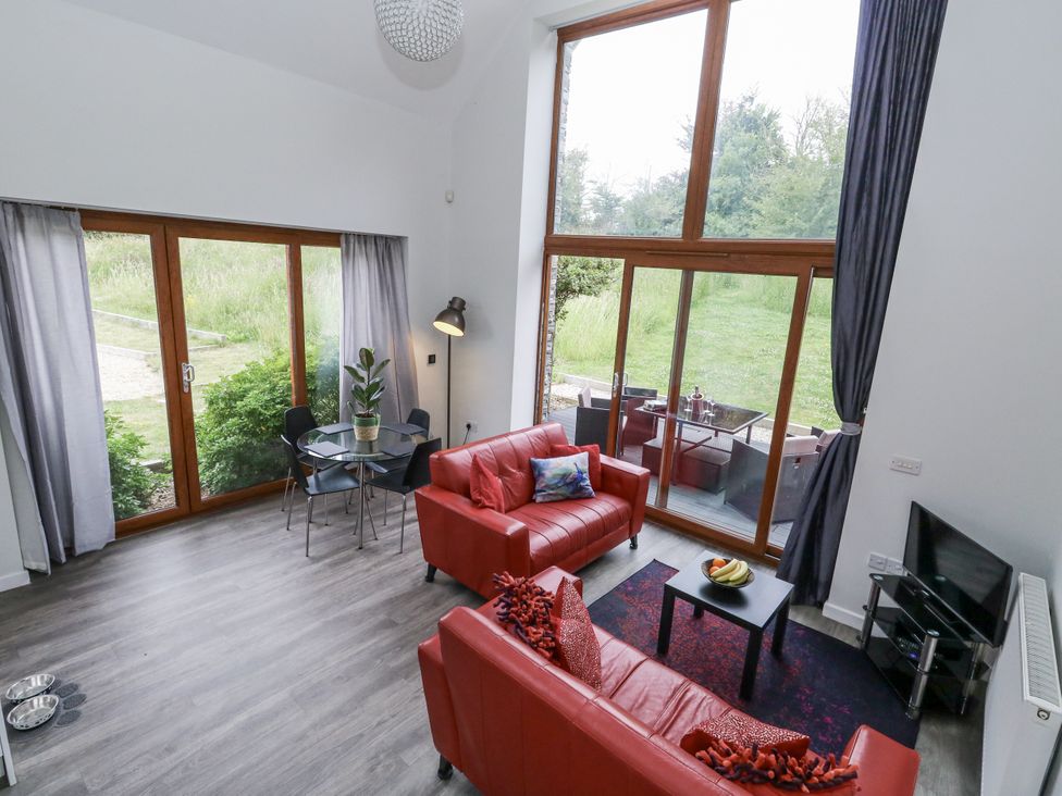A living room with a sofa a dining table and a television at Budmouth Upwey near Weymouth