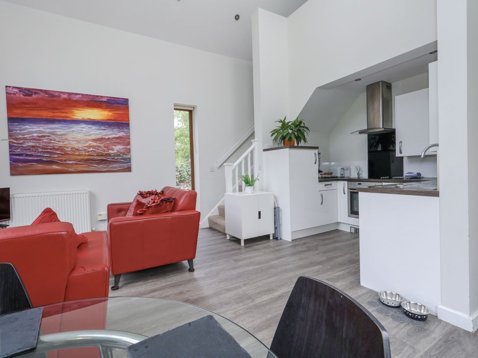 A living room with a sofa and kitchen area at Budmouth Upwey near Weymouth