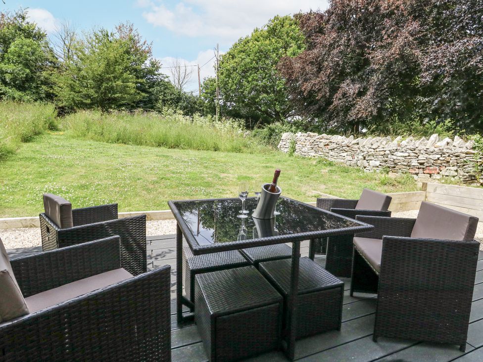 A table with chairs and a bottle cooler in a garden at Budmouth Upwey near Weymouth