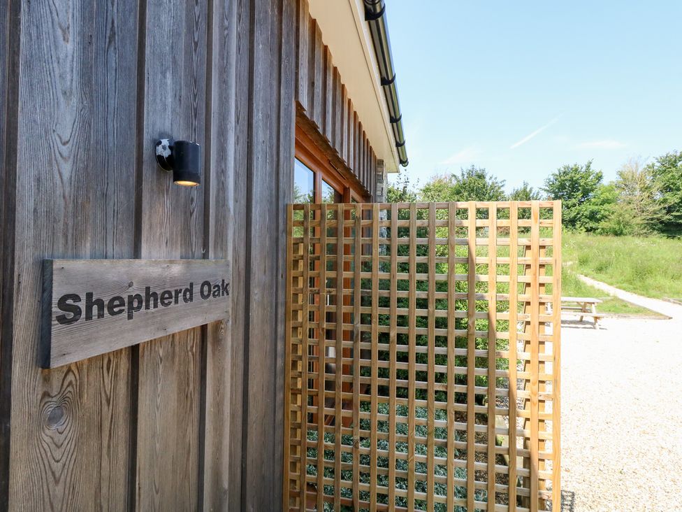 A wooden wall with a sign and trellis at Shepherd Oak in Upwey near Weymouth