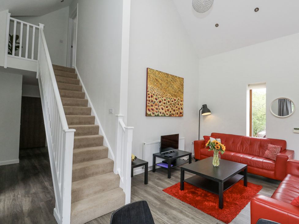 A living room with a red sofa and a staircase at Everdene Upwey near Weymouth