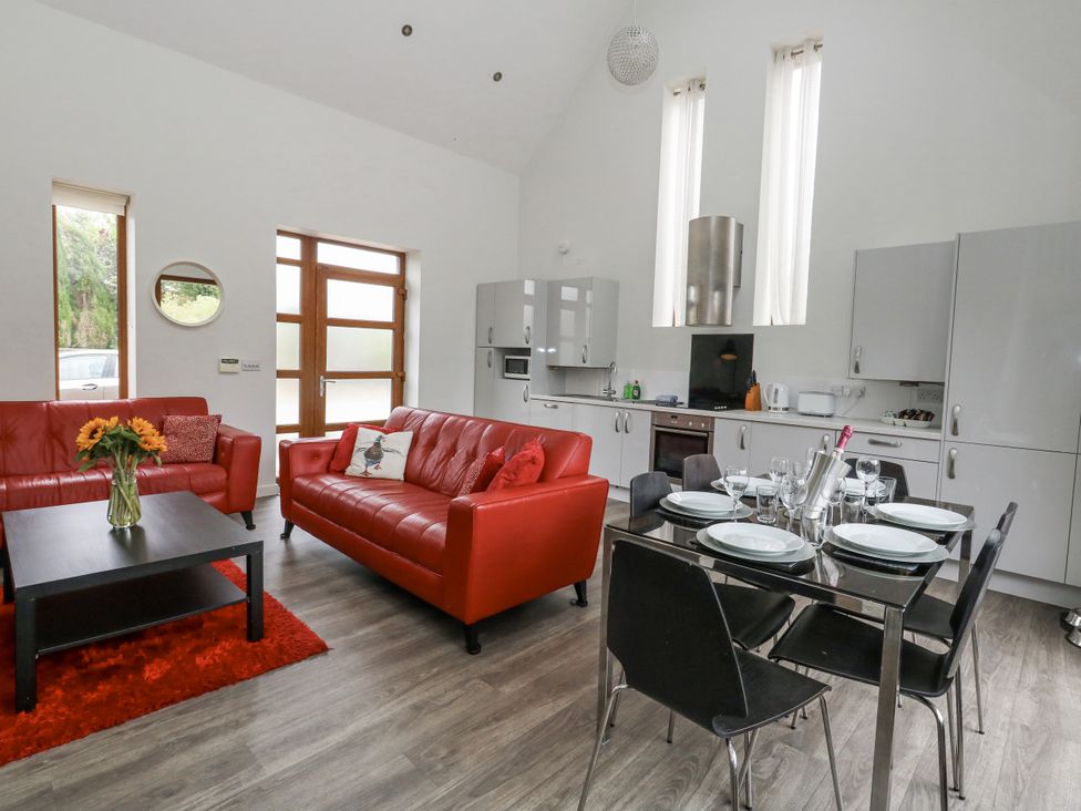 A living room with red sofas and a dining area at Everdene Upwey near Weymouth