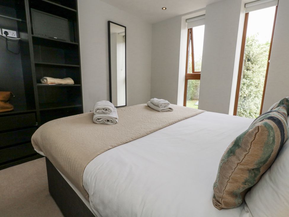 A bedroom with a bed, towels, and shelves at Everdene Upwey near Weymouth