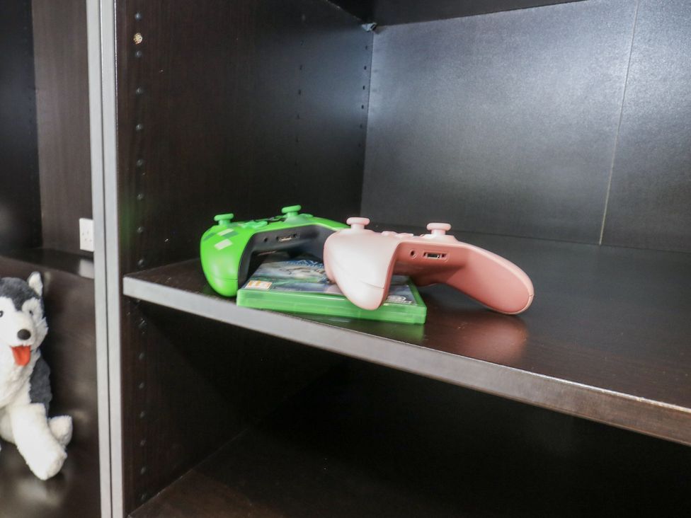 A shelf with game controllers and a plush toy at Everdene in Upwey near Weymouth