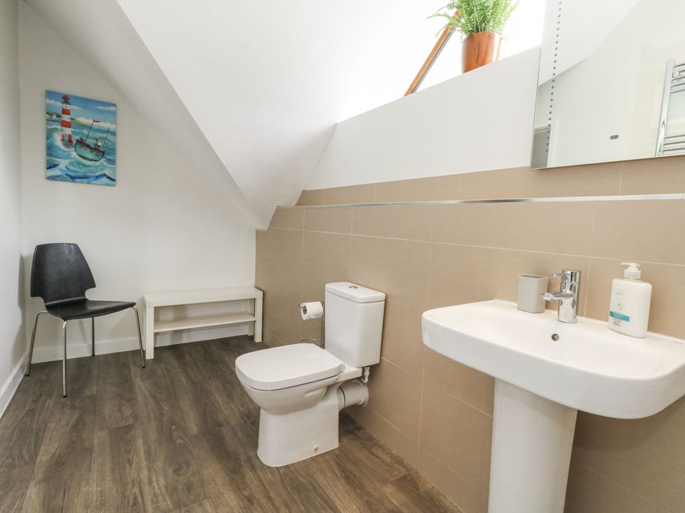 A bathroom with a toilet, sink, and chair at Everdene in Upwey near Weymouth
