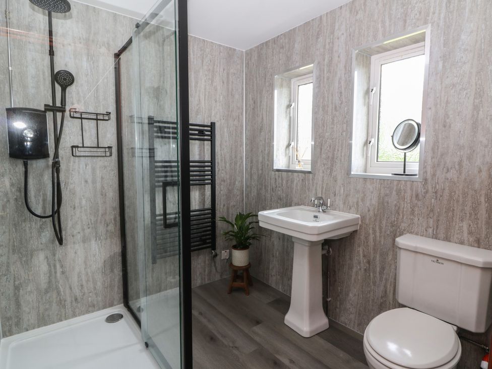 A bathroom featuring a shower, toilet, and sink at Red Kite Cottage Howey near Llandrindod Wells