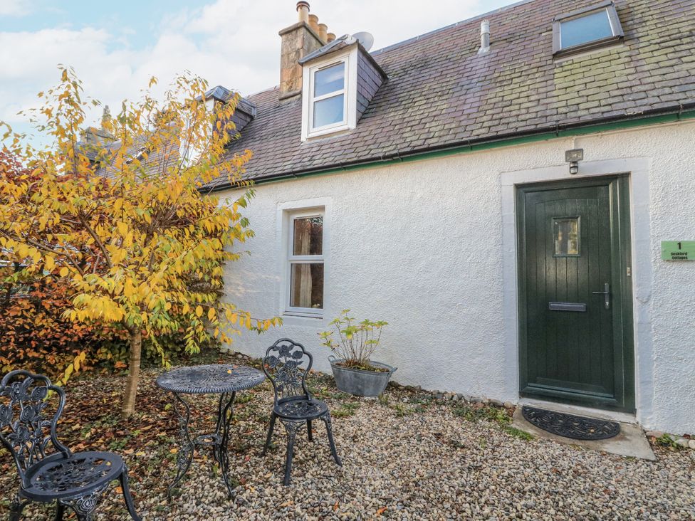 An outdoor area with a table and chairs at Deskford Cottage in Nairn