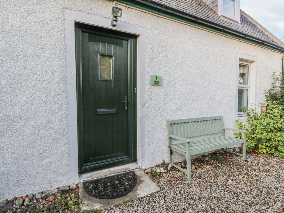 An exterior view with a green door and bench at Deskford Cottage Nairn