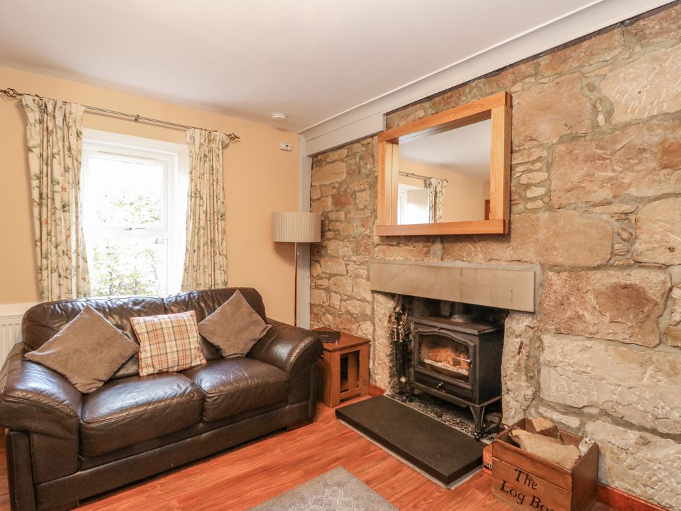 A living room with a fireplace and sofa at Deskford Cottage Nairn