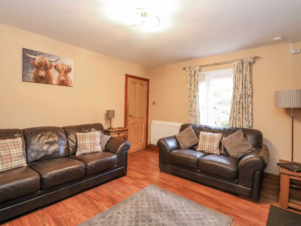 A living room with sofas and a lamp at Deskford Cottage in Nairn