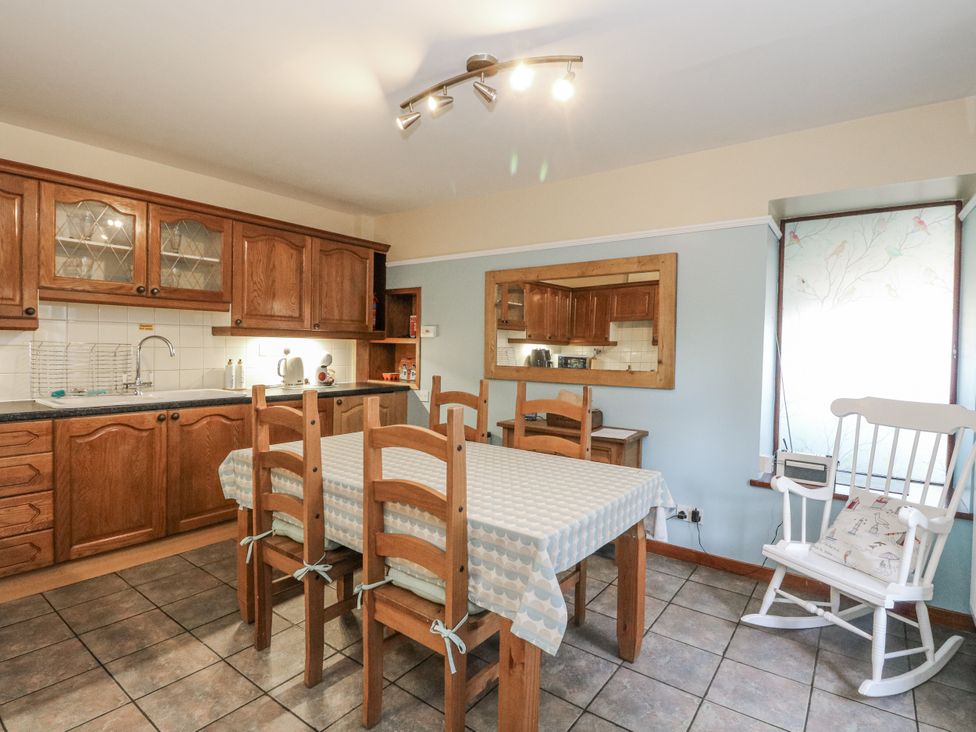 A kitchen with wooden cabinets and a table with chairs at Deskford Cottage in Nairn