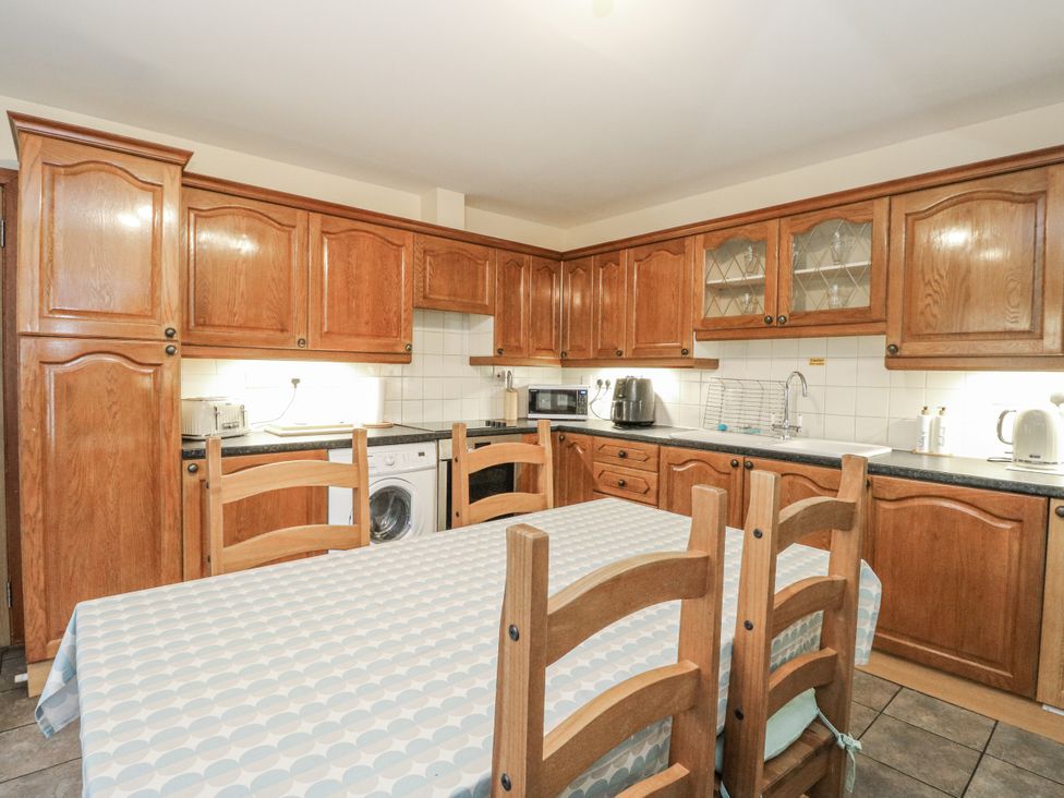 A kitchen with wooden cabinets and appliances at Deskford Cottage in Nairn