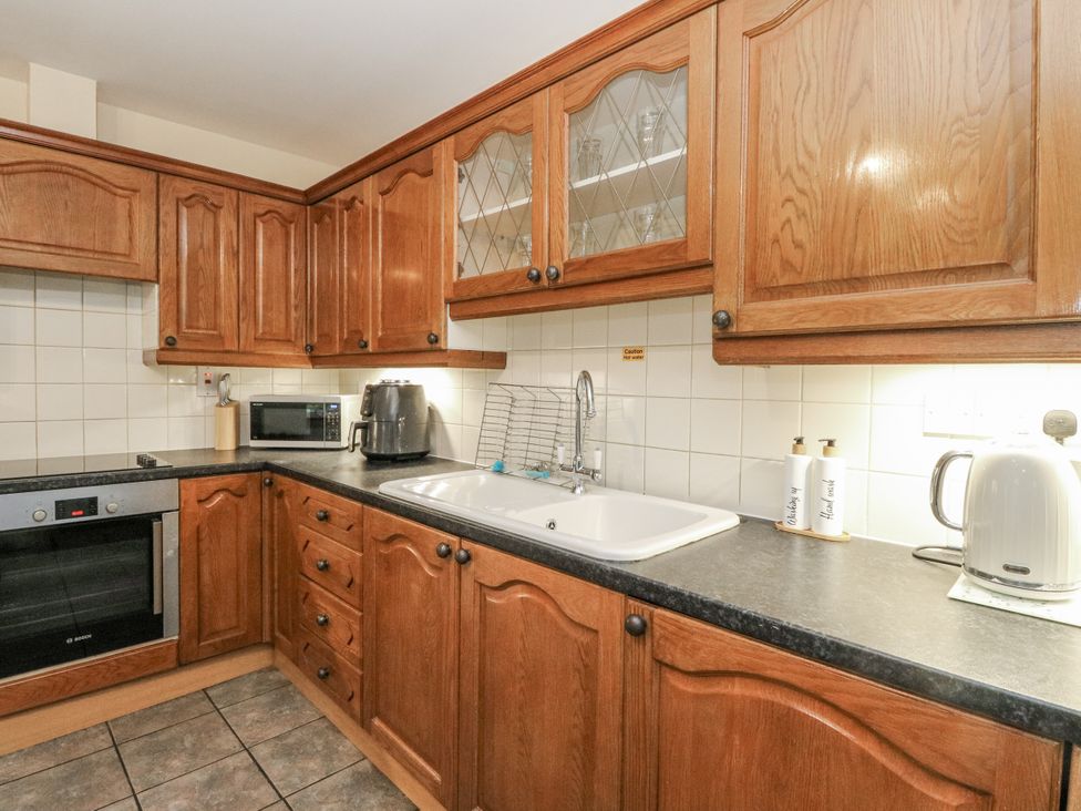 A kitchen with cabinets, sink, kettle, and microwave at Deskford Cottage Nairn