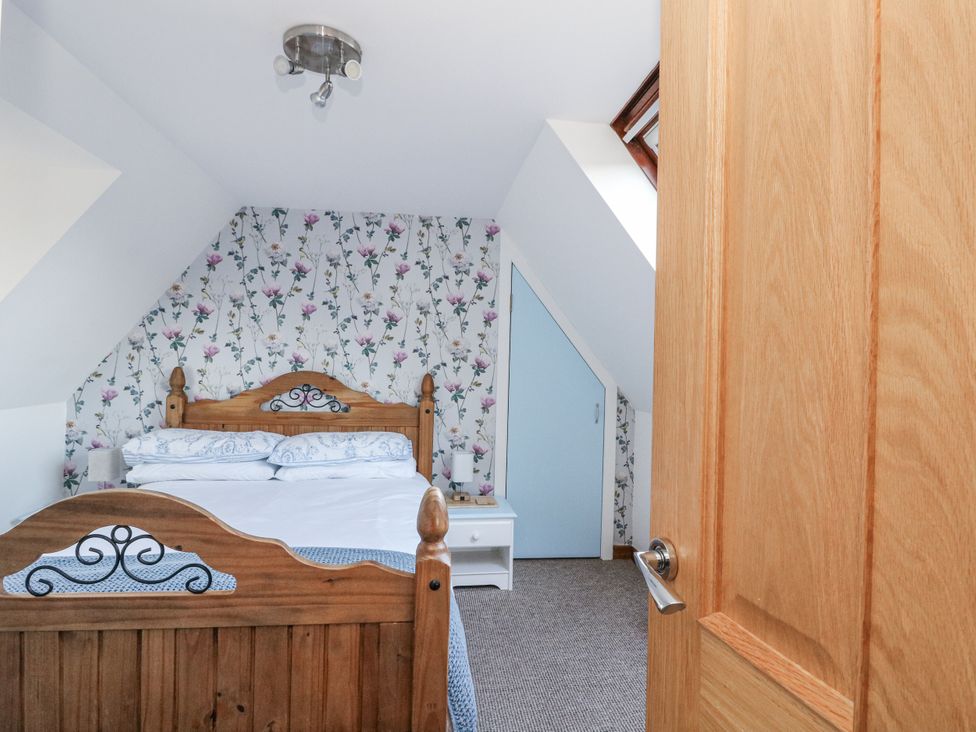 A bedroom with a bed and door at Deskford Cottage in Nairn