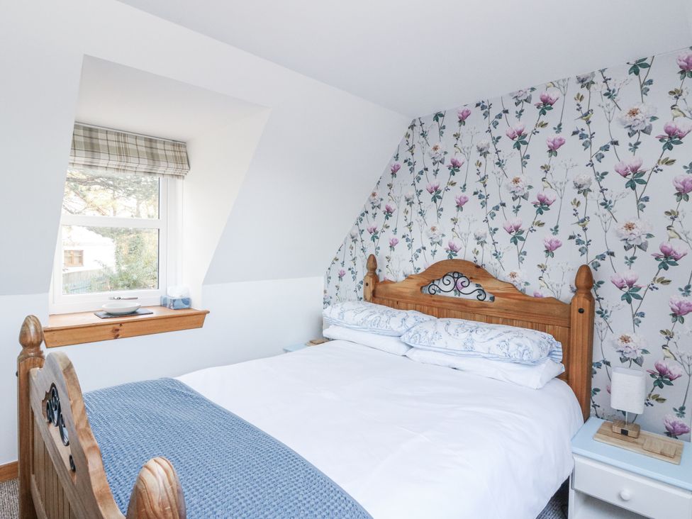 A bedroom with a bed and window at Deskford Cottage in Nairn