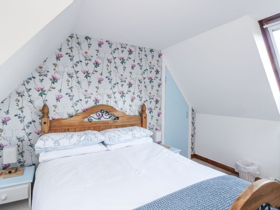 A bedroom with a bed and a nightstand at Deskford Cottage in Nairn