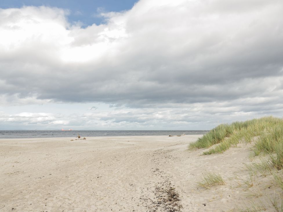 A beach with sand dunes and ocean at Deskford Cottage in Nairn