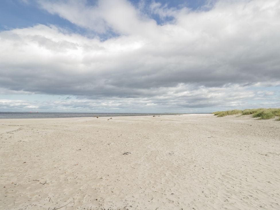A beach with sand and sea at Deskford Cottage in Nairn