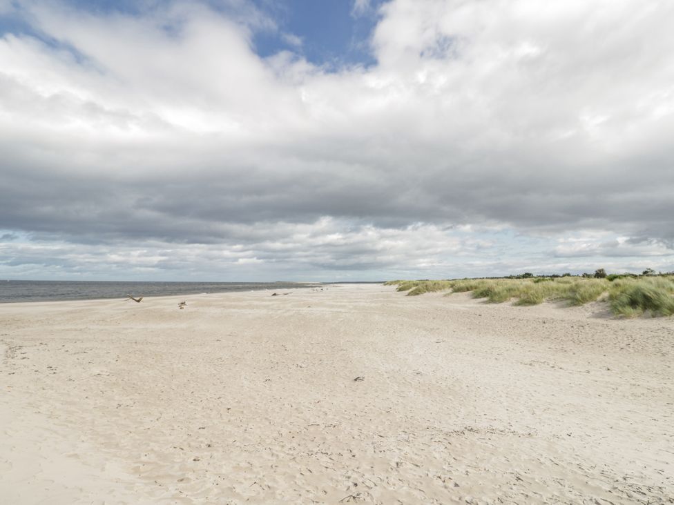 A beach with sand and grass at Deskford Cottage in Nairn