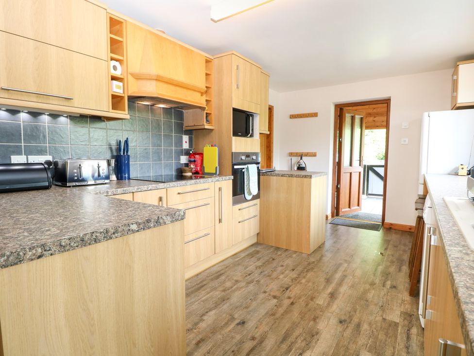 A kitchen with wood cabinets and appliances at Dragonfly Lodge in Whinburgh near Dereham