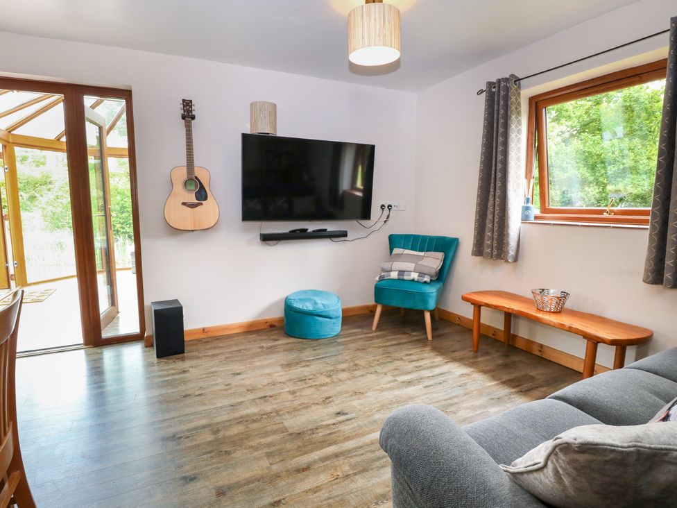 A living room with a television and a guitar at Dragonfly Lodge Whinburgh near Dereham